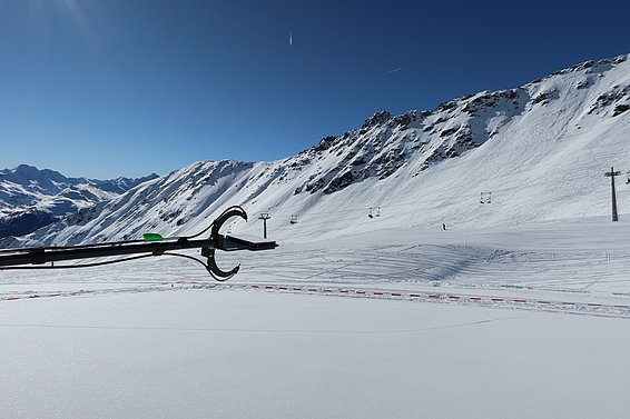 Sensorarm im Vordergrund vor schneebedeckten Bergen und Skilift bei klarem Himmel