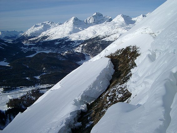 Gleitschneeriss an einem steilen, schneebedeckten Berghang im Val Muragl mit schneebedeckten Bergen im Hintergrund