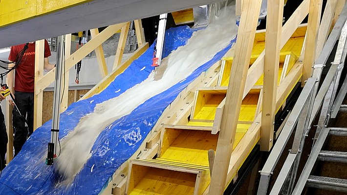 Blaues, spiegelverkehrtes Modell der Region von Blatten. Von oben kommt ein Matschgemisch den künstlichen Hang herunter.