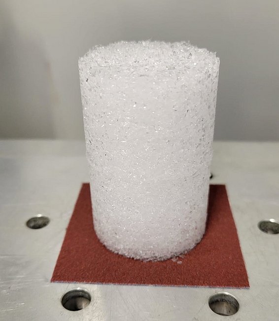 Zylindrische Schneeprobe mit körniger Struktur auf Metallplatte