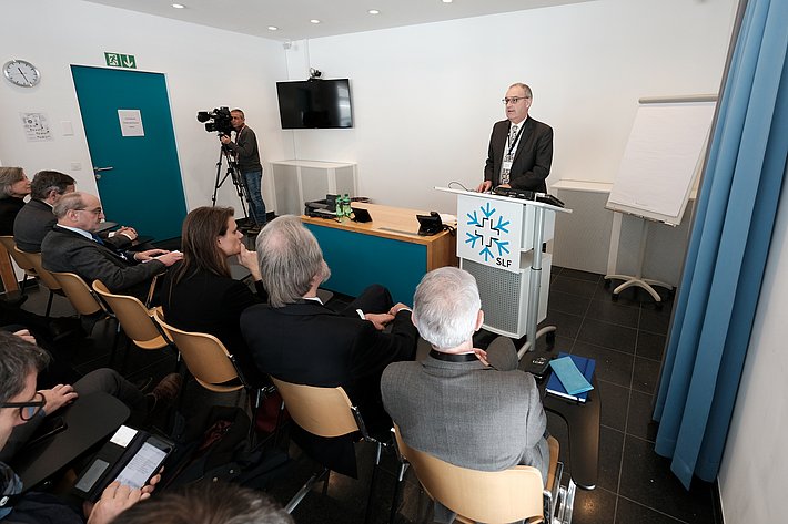 Bundesrat Parmelin steht an einem SLF-Rednerpult und spricht vor Zuhörern