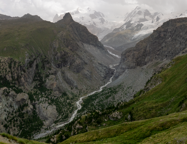 Gletscherlandschaft des Gornergletschers im Jahr 2022 mit schneebedeckten Bergen, steilen Felswänden und einem schmalen Fluss im Tal