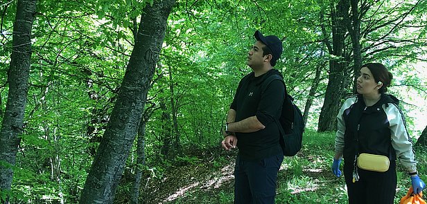 Zwei Personen im Wald, nachdenklich nach oben schauend.