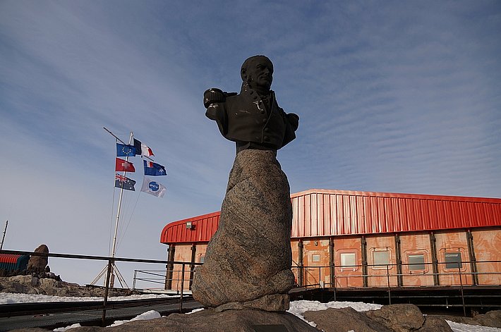 Adminral Dumont, Gründer der Station. Im Hintergrund: Ein Schweizer reicht, damit die Schweizer Flagge hinzukommt.