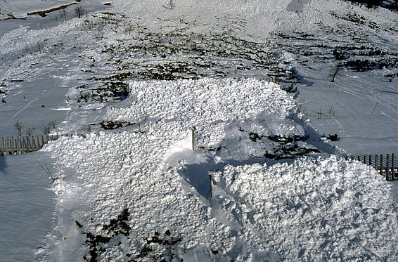 Campo innevato dopo una valanga con superfici innevate irregolari e terreno parzialmente visibile