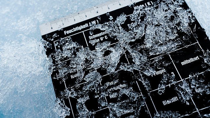 Schwarze Feuchtigkeits- und Temperaturtafel mit zerbrochenem, transparentem Eis darauf, umgeben von Schnee.