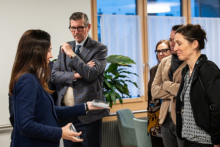 Gebannt lauschen SUPSI-Präsident Giovanni Merlini und die Mathematikerin und ehemalige Leiterin der COVID-Taskforce Tanja Stadler der EMPA-Forscherin Nathalie Casas, wie diese CO<sub>2</sub> als Rohstoff der Zukunft aus der Atmosphäre fördern will. (Foto: Luzia Schär)